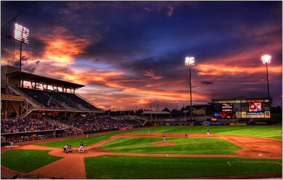 A baseball field under stadium lights at dusk